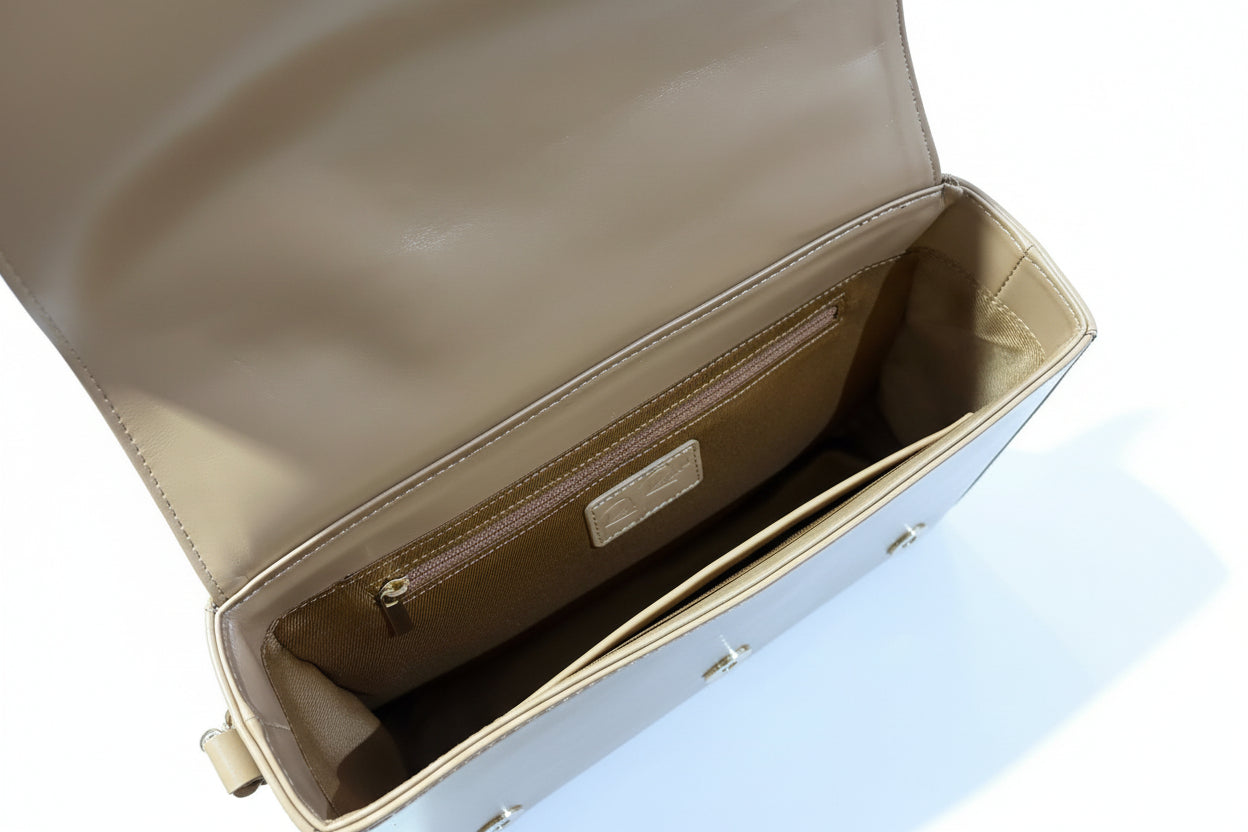 Beige leather handbag with visible brand logo on a wooden surface